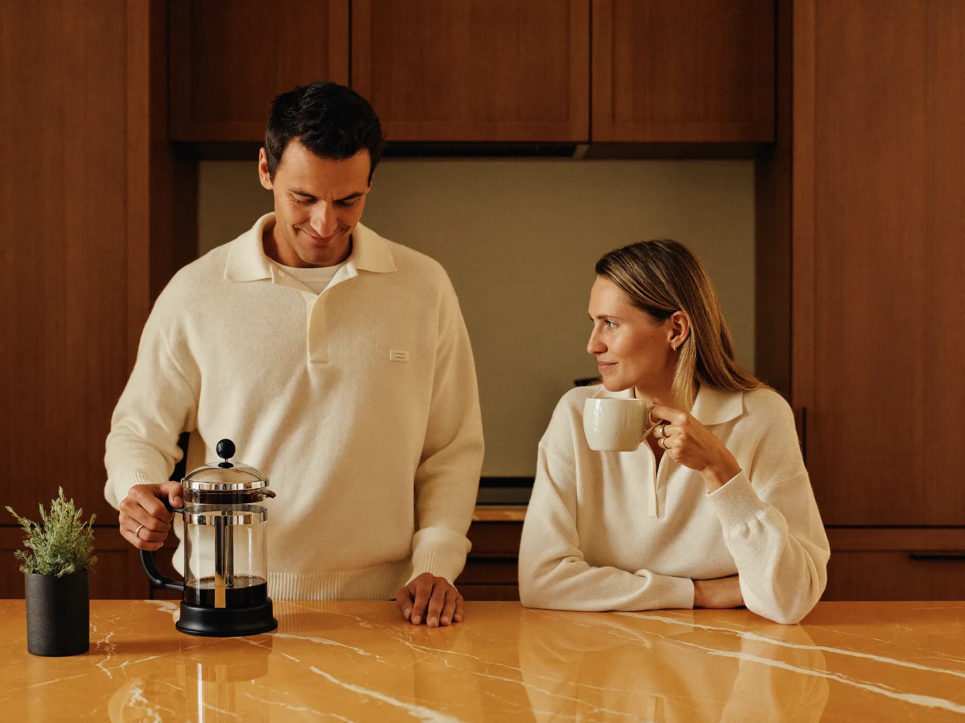 A couple in their 40s in a sunlit kitchen on a Saturday morning — the shared everyday rhythm that supports balanced hormones.
